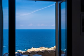 A view through a window of a coastal landscape with the sea and rocky shoreline. - Holiday Home "Villetta Duplex Breathtaking View" with Sea View, 2 Private Terraces and Wi-Fi (Costa Paradiso)