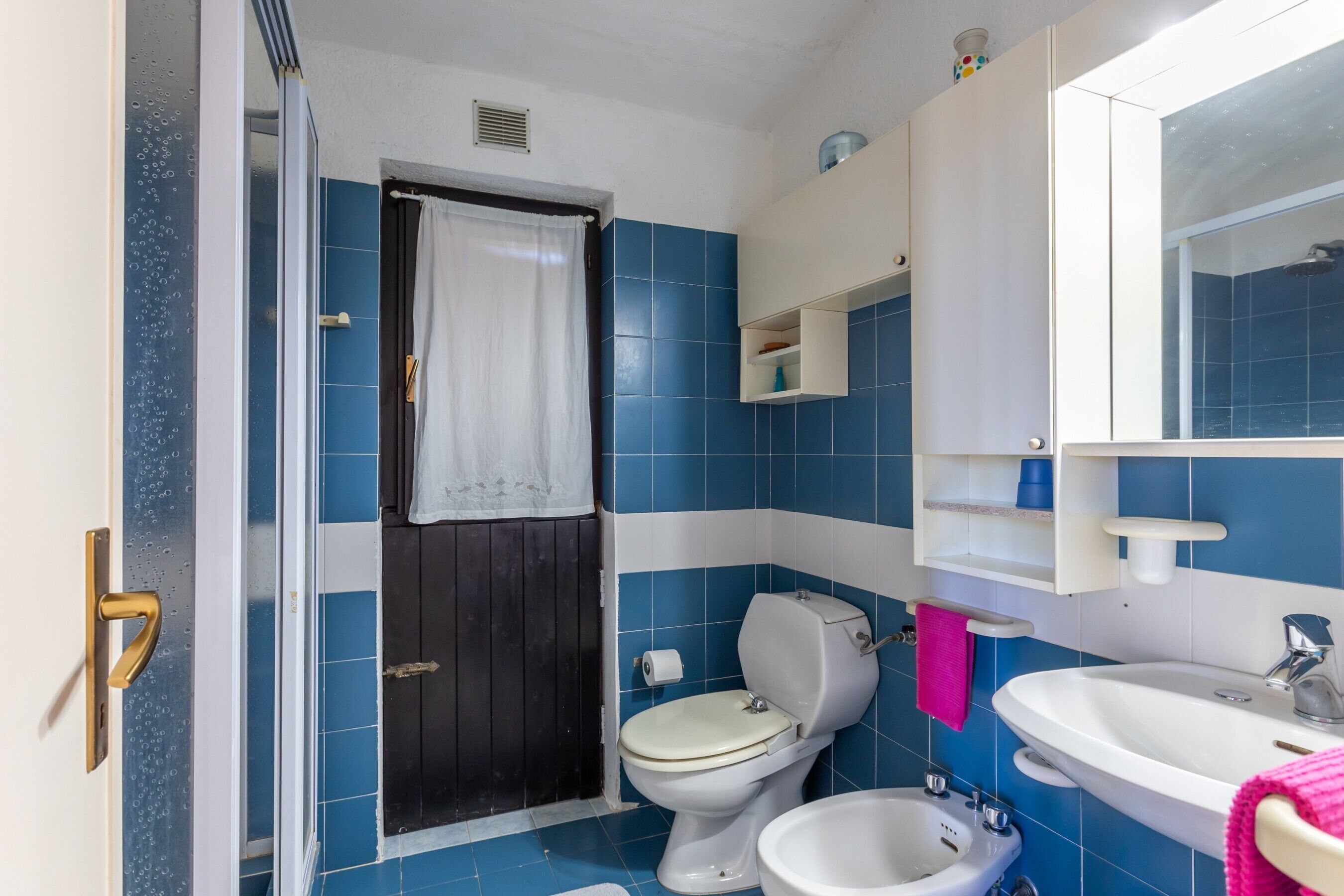A bathroom with a toilet, bidet, sink, and mirror.