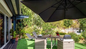 An outdoor patio with wicker furniture, a table, and an umbrella.