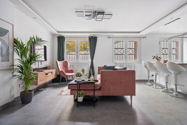 Un salon moderne avec un canapé, des fauteuils, une table basse et des plantes en pot.