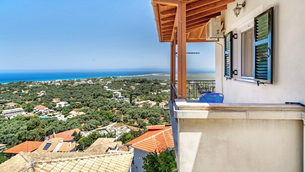 Un balcón con vista al mar y casas circundantes.
