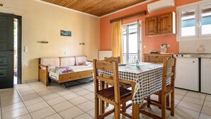 Una habitación con cama, una mesa de comedor con sillas, una zona de cocina y una ventana con cortinas.