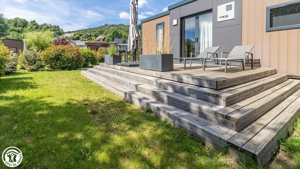 Ein modernes Gebäude mit einer Holterrasse, Sitzgelegenheiten im Freien und einer Treppe zum Eingang.
