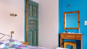 Un dormitorio con una cama, un aparador de madera, un espejo y una pared azul.