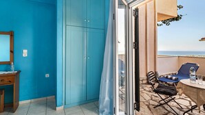 Una habitación con pared azul, un escritorio de madera, una silla, una mesa y vista al mar a través de un ventanal.