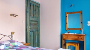 Un dormitorio con una cama, un aparador de madera, un espejo y una pared azul.