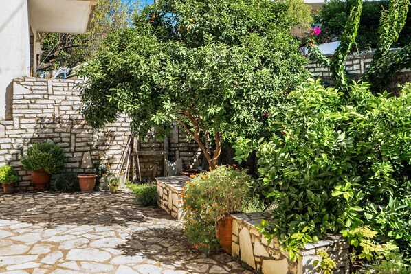 A stone-paved courtyard with potted plants and a stone wall.