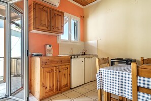 A kitchen with wooden cabinets, a window, a dishwasher, and a table with a checkered tablecloth.