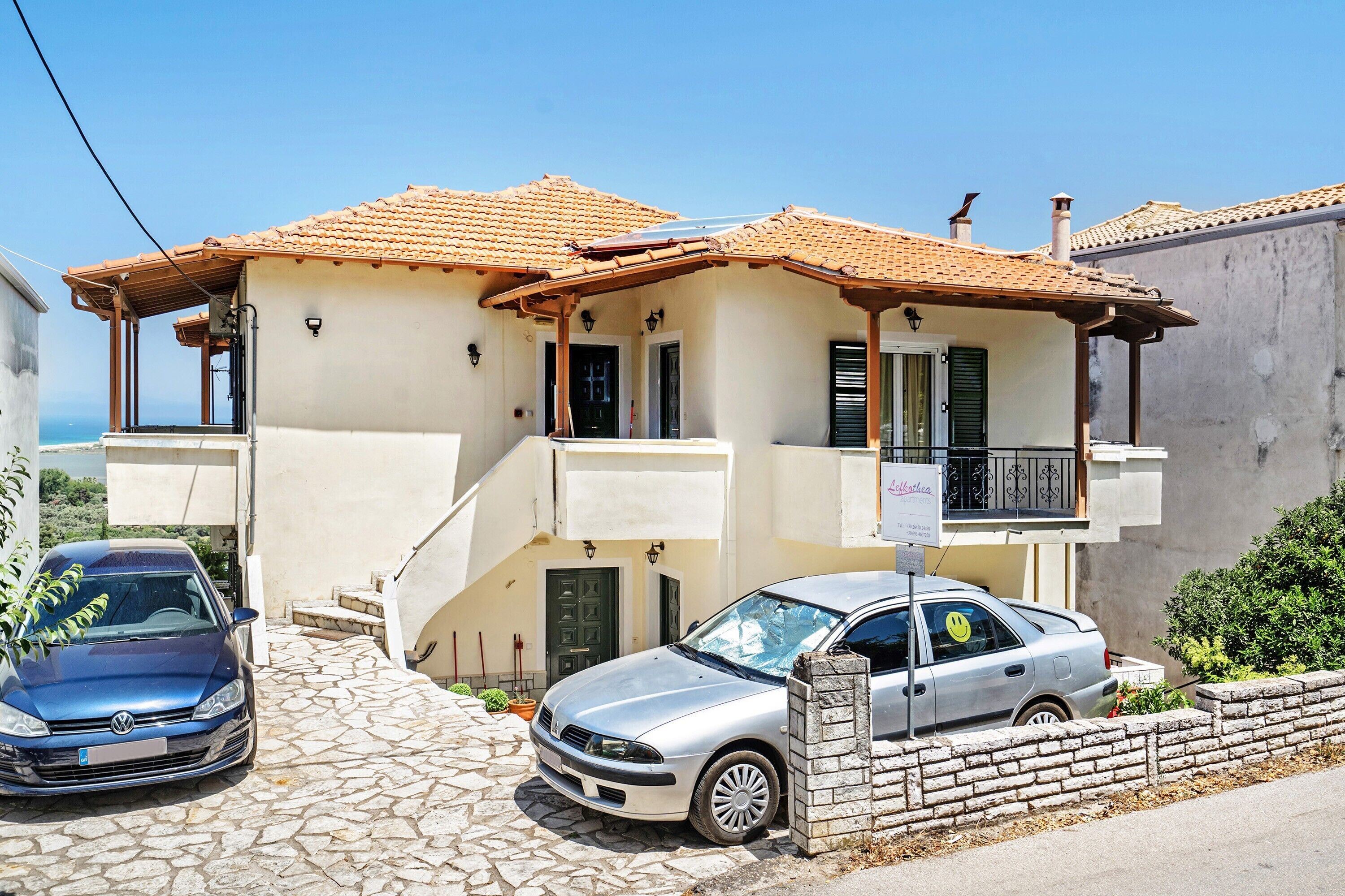 Un bâtiment à deux étages, doté d’un toit recouvert de tuiles, d’un balcon et d’une voiture garée devant.