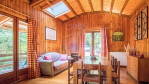 Eine Holzhütte mit Essbereich, einer Couch und einem Kamin.