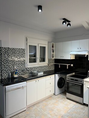 Una cocina moderna con lavavajillas, lavadora, horno y un salpicadero de azulejos negros.