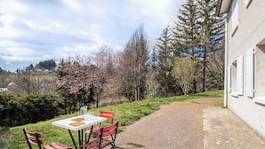 A patio with a table and chairs, a gravel path, and trees with pink blossoms.