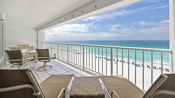 Un balcon donnant sur la plage, avec des chaises et une rambarde.