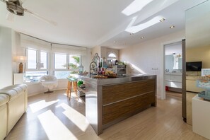 Una cocina moderna con una isla central, ventanas amplias y vistas al mar.