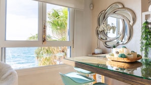 Habitació moderna amb taula de vidre, un mirall gran i vista a l'oceà.