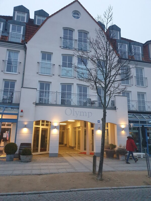 A building with the sign "Olymp" at the entrance, featuring a modern architectural style with multiple windows and balconies.