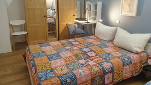 Et soveværelse med seng, skrivebord, stol og garderobe.