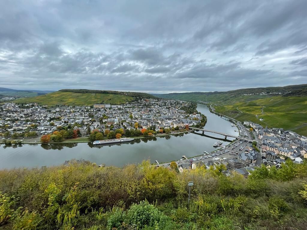 Un pueblo a orillas del río con un puente, el río y vegetación circundante.