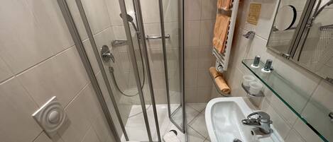 Un baño con cabina de ducha de vidrio, un lavamanos blanco y un inodoro.