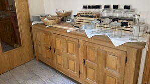 A wooden cabinet with glass jars, baskets, and kitchen utensils.