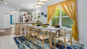 A modern kitchen with white cabinets, a wooden island, and a dining area with a table set for four.