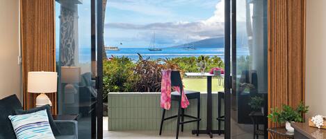 Ein Zimmer mit Meerblick, eine Essecke mit Stühlen und Tisch sowie eine Couch mit Kissen.