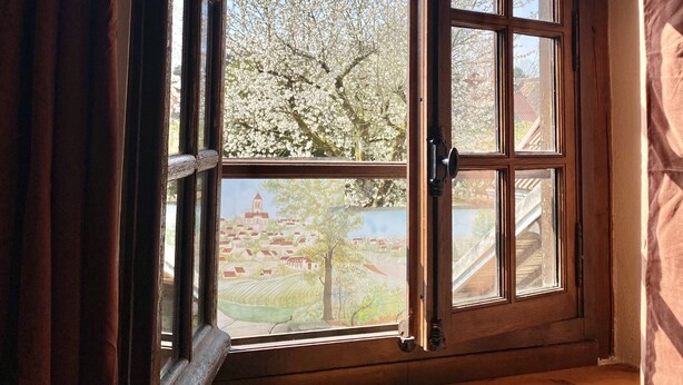 Une fenêtre donnant sur un village et des arbres.