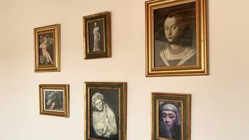 Uma parede com cinco obras de arte emolduradas, de tamanhos e temas diferentes.