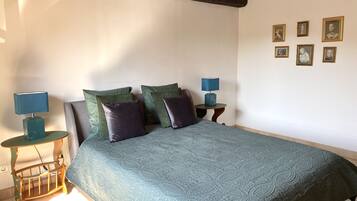 Une chambre à coucher avec un grand lit, deux tables de chevet avec des lampes et un mur orné de tableaux.