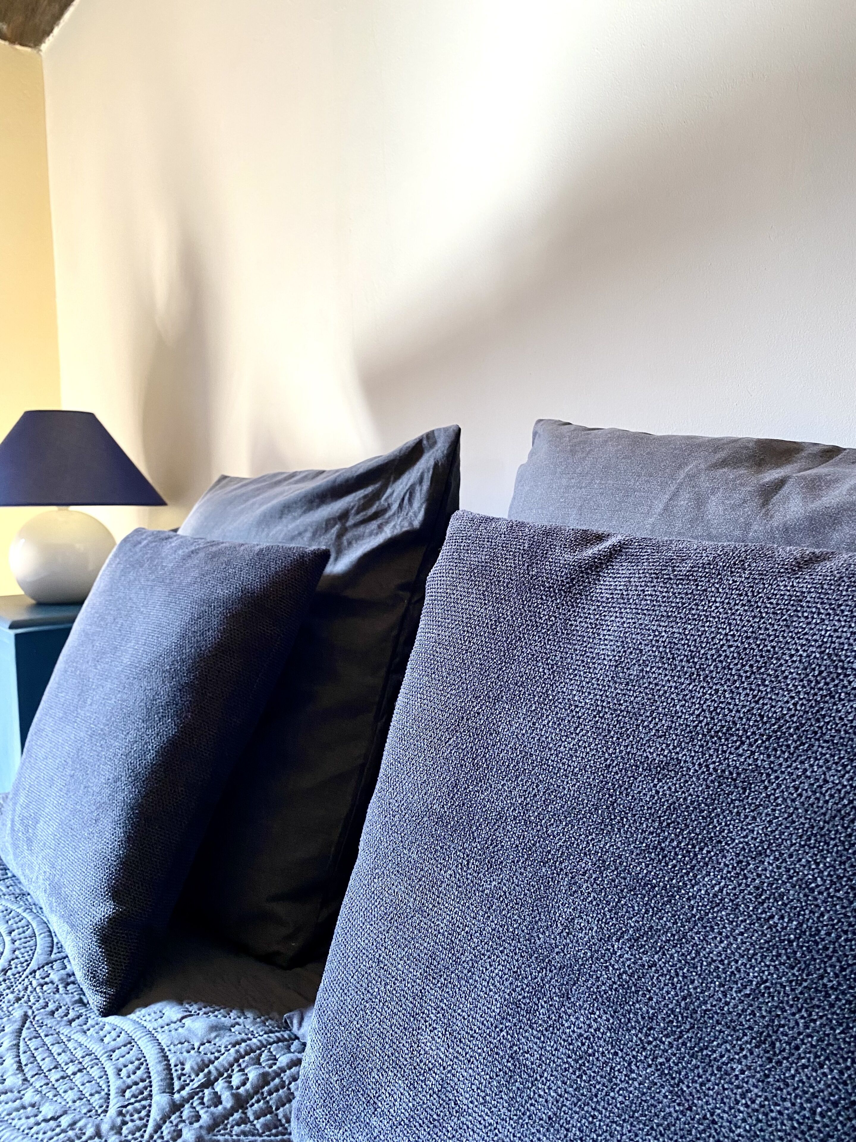 A bed with two pillows and a lamp on a bedside table.
