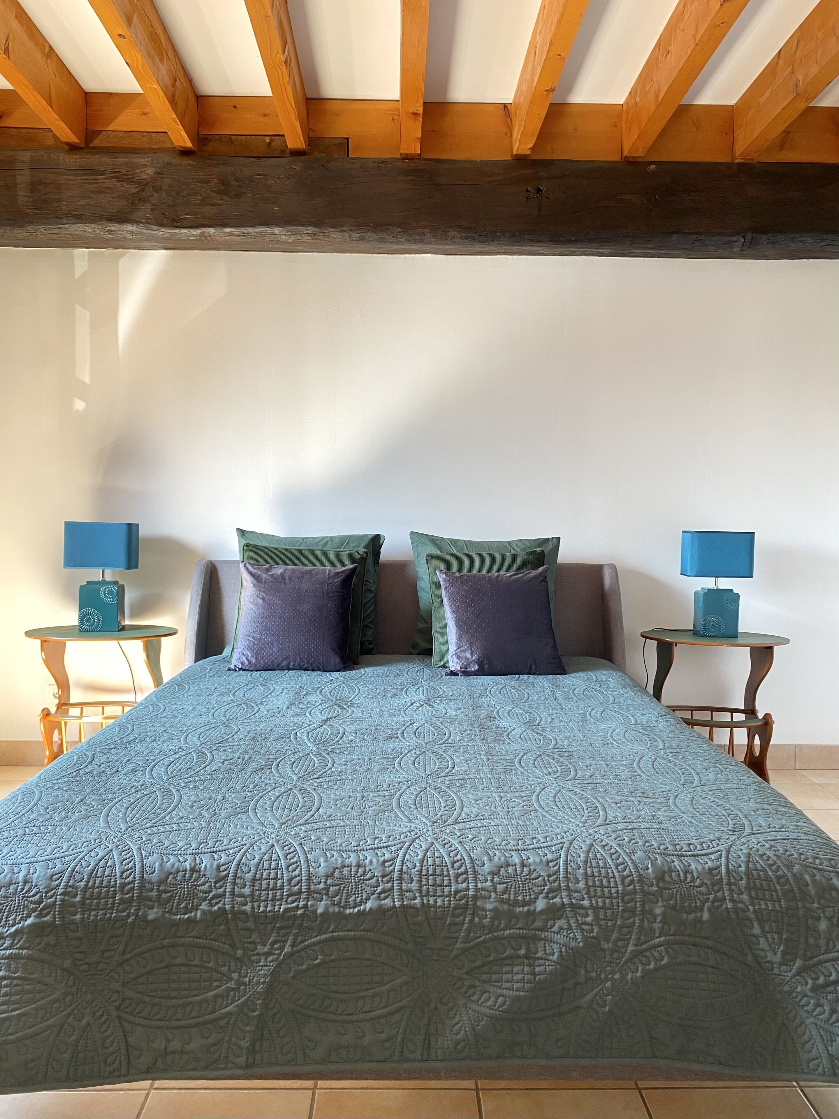 Un dormitorio con una cama grande, dos mesitas de noche con lámparas y un techo de madera.
