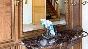 Un miroir à cadre en bois, doté d’un socle en marbre, qui reflète un escalier et une porte.
