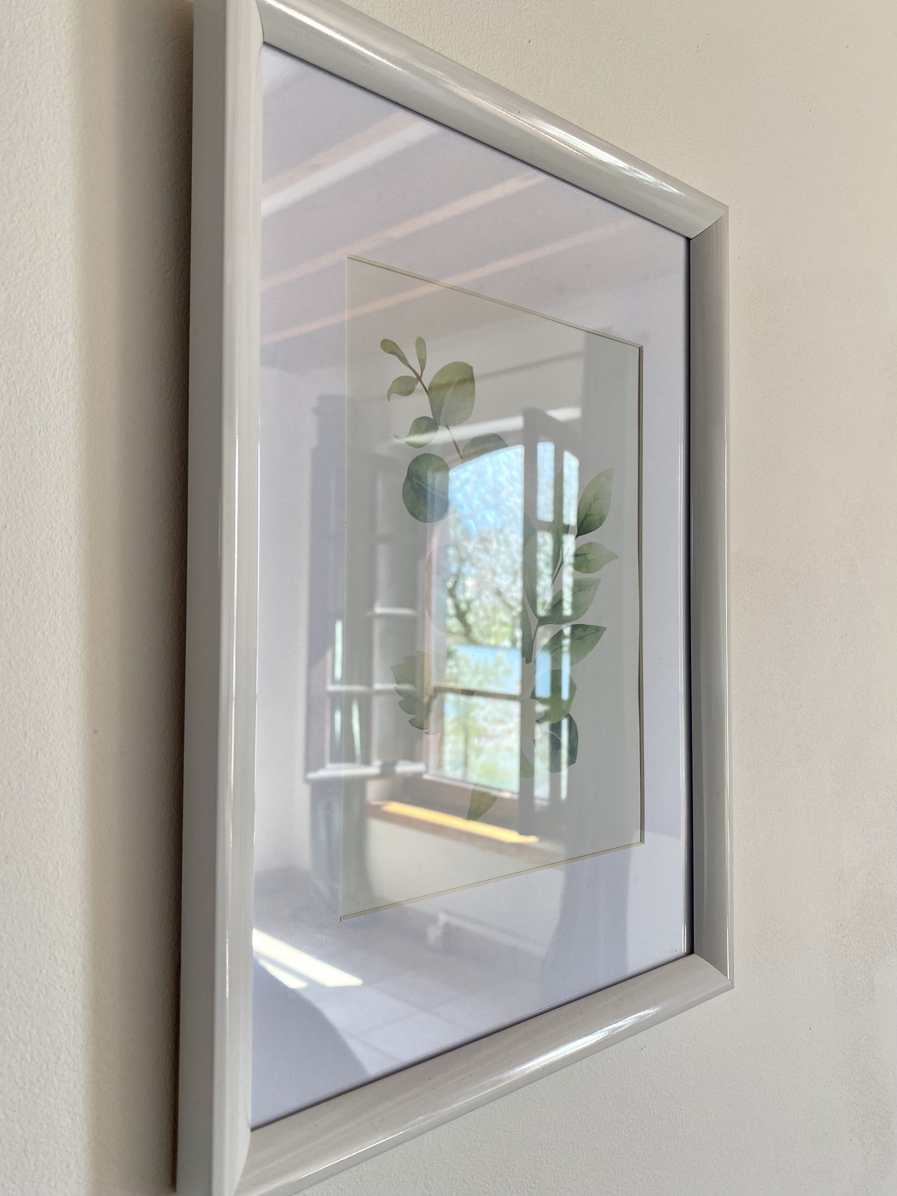 Un cuadro enmarco con vista a un edificio y una planta a través de una ventana.