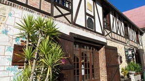 Un bâtiment traditionnel à colombages, doté d’une grande porte en bois et de fenêtres, et entouré de plantes en pot.