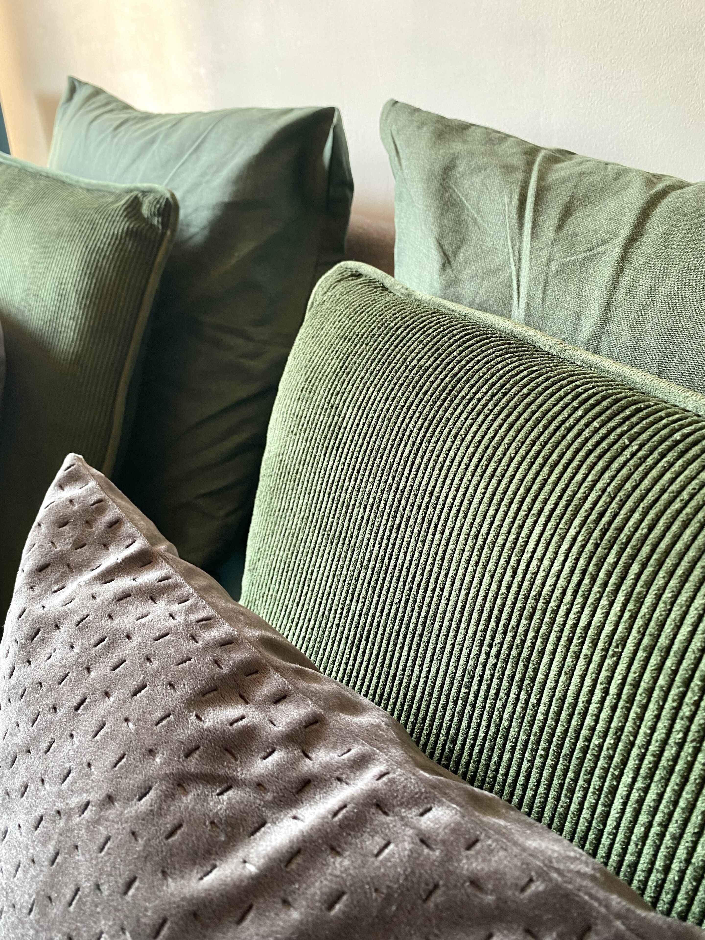 A close-up of a green upholstered sofa with a textured pattern.