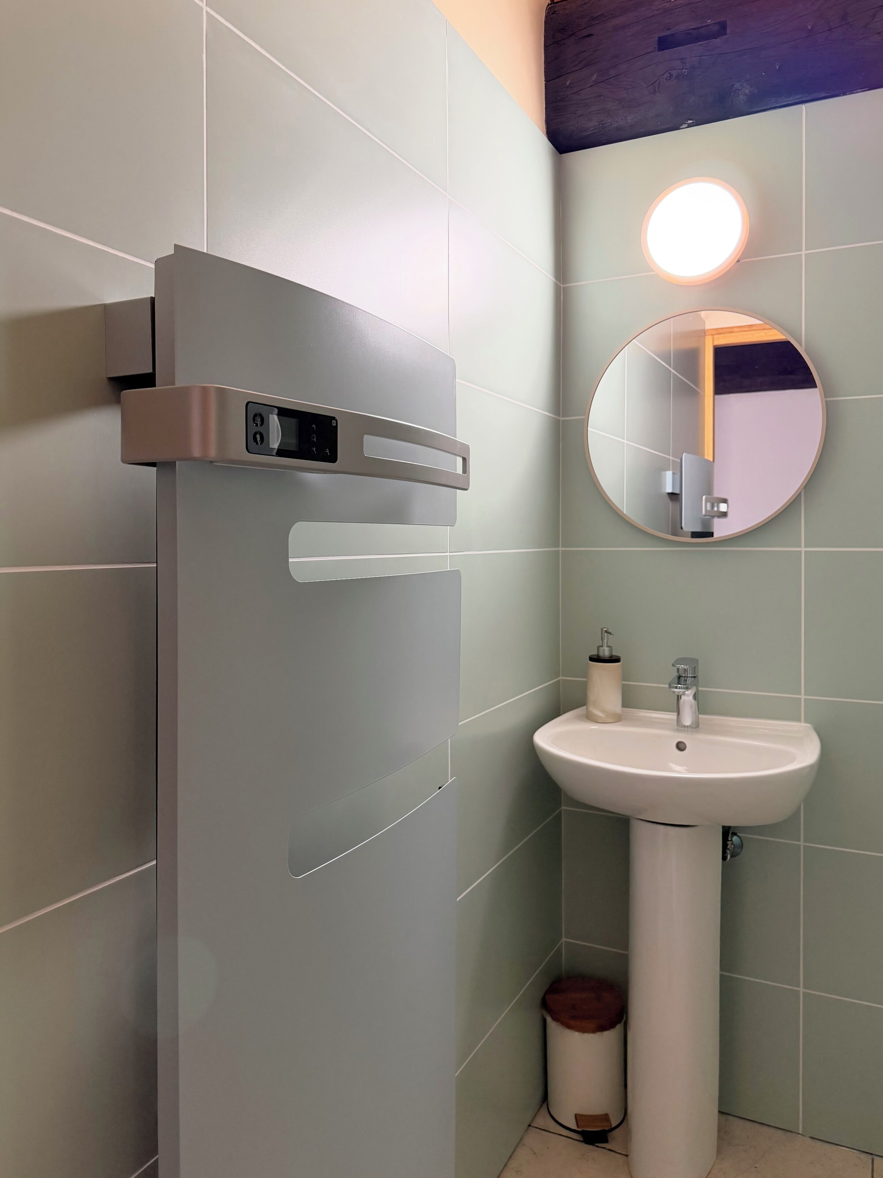 A bathroom with a white sink, a mirror, and a wall-mounted light fixture.