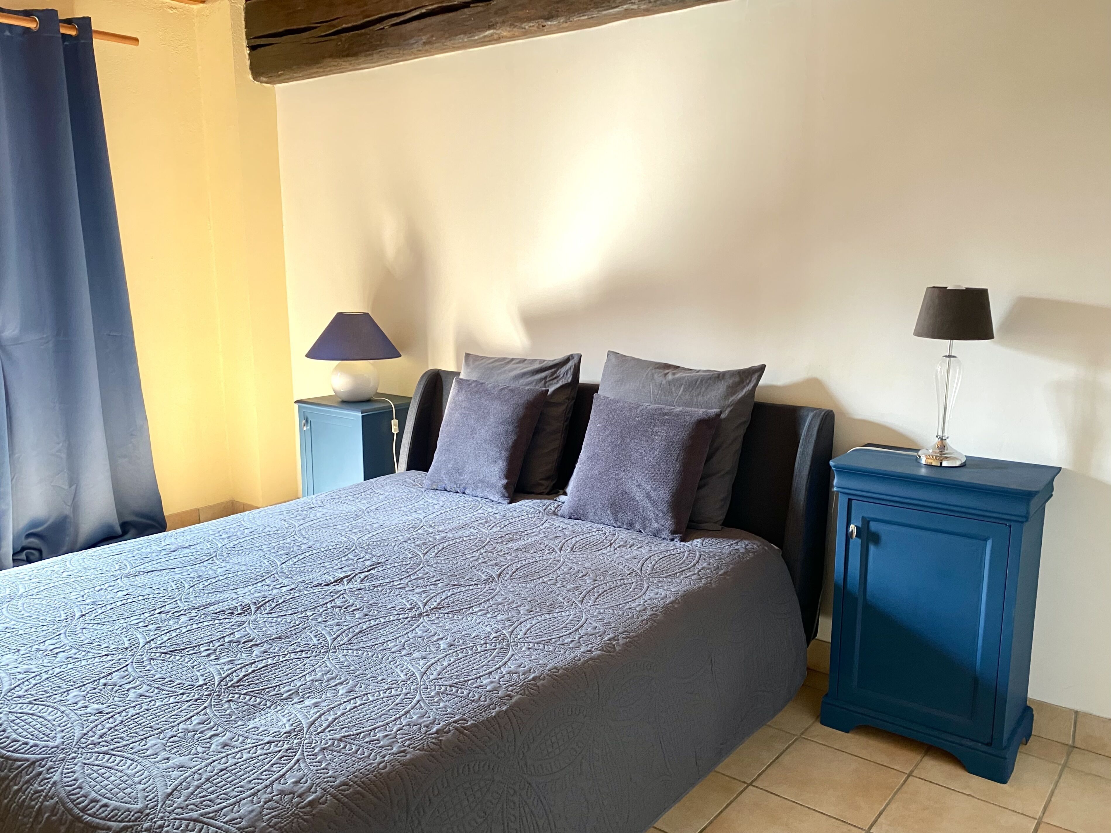 Une chambre à coucher avec un lit, deux tables de chevet et une commode.