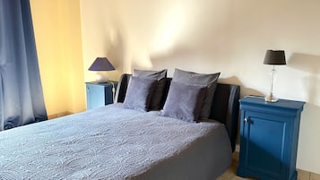 Une chambre à coucher avec un lit, deux tables de chevet et une commode.