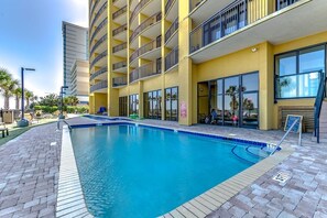 A hotel with a swimming pool, a yellow exterior, and a balcony with a view of the pool.
