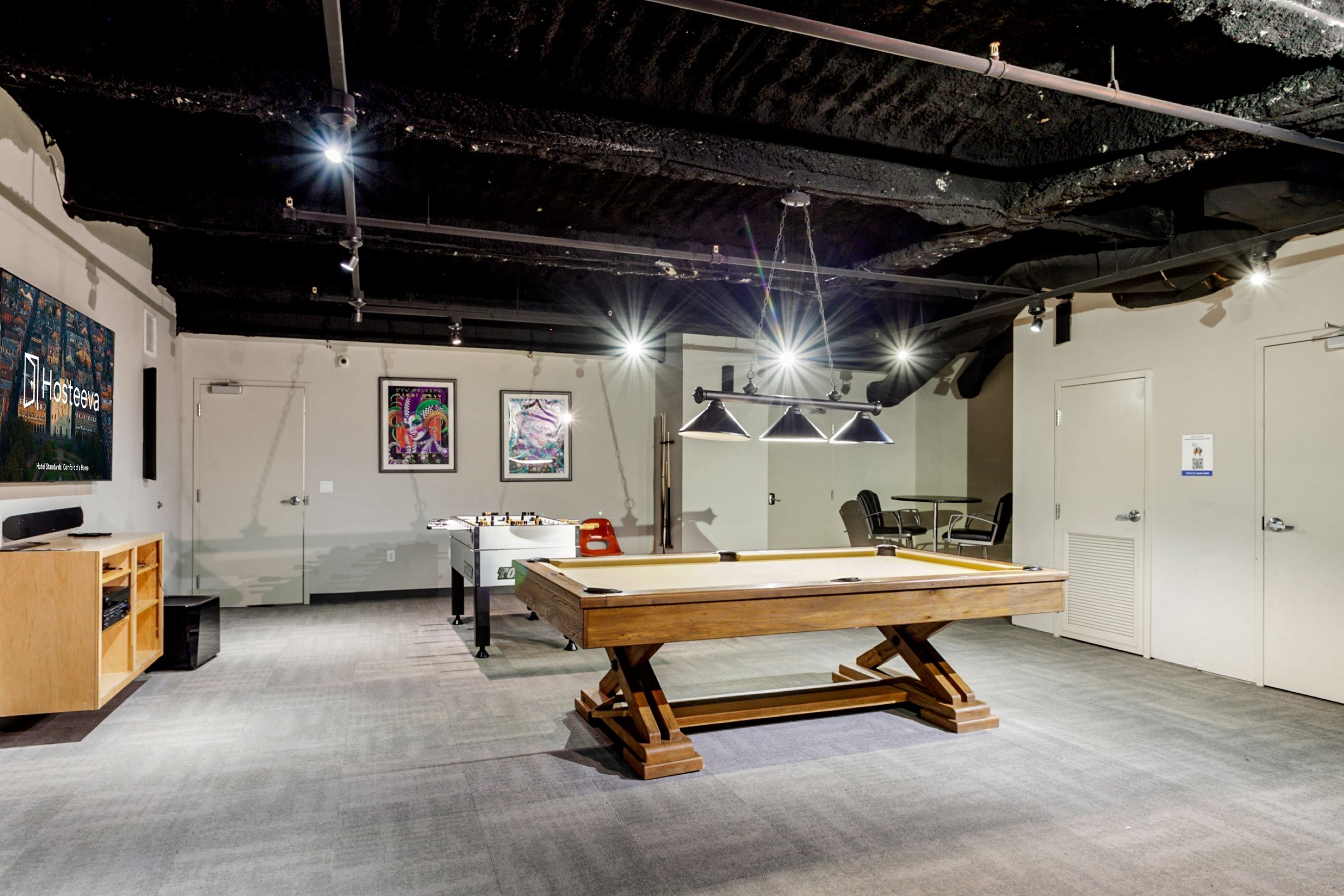 A billiards table in a room with a high ceiling, artwork on the walls, and a pool table in the background.