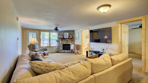 A living room with a fireplace, a sofa, a TV, and a stone wall. - Relaxing Getaway with that UP North Feel! (Beaverton)