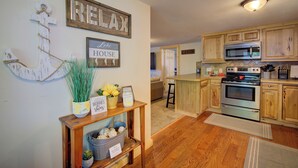 A kitchen with wooden cabinets, a stainless steel oven, and a microwave. There is a sign on the wall that reads "REELAX" and another that says "House." - Relaxing Getaway with that UP North Feel! (Beaverton)