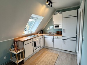 Eine kleine Küche mit Fenster, einer Mikrowelle und einem Kühlschrank.