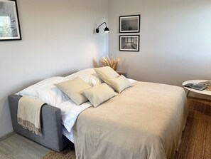 Ein ordentlich eingerichtetes Schlafzimmer mit einem Bett, Nachttischen und Wandleuchten.