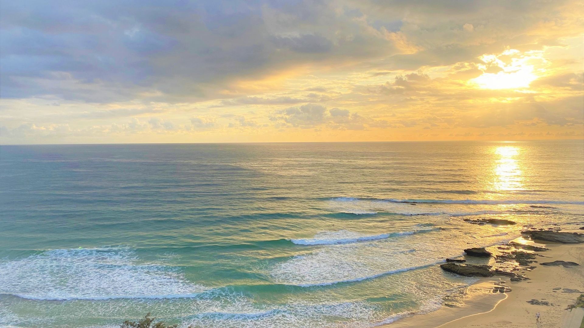 A beach with waves and a sunset.