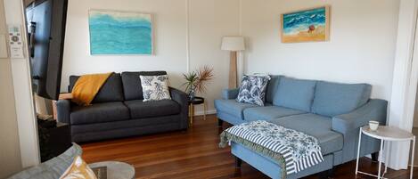 A living room with two sofas, a coffee table, a TV, and artwork on the walls.