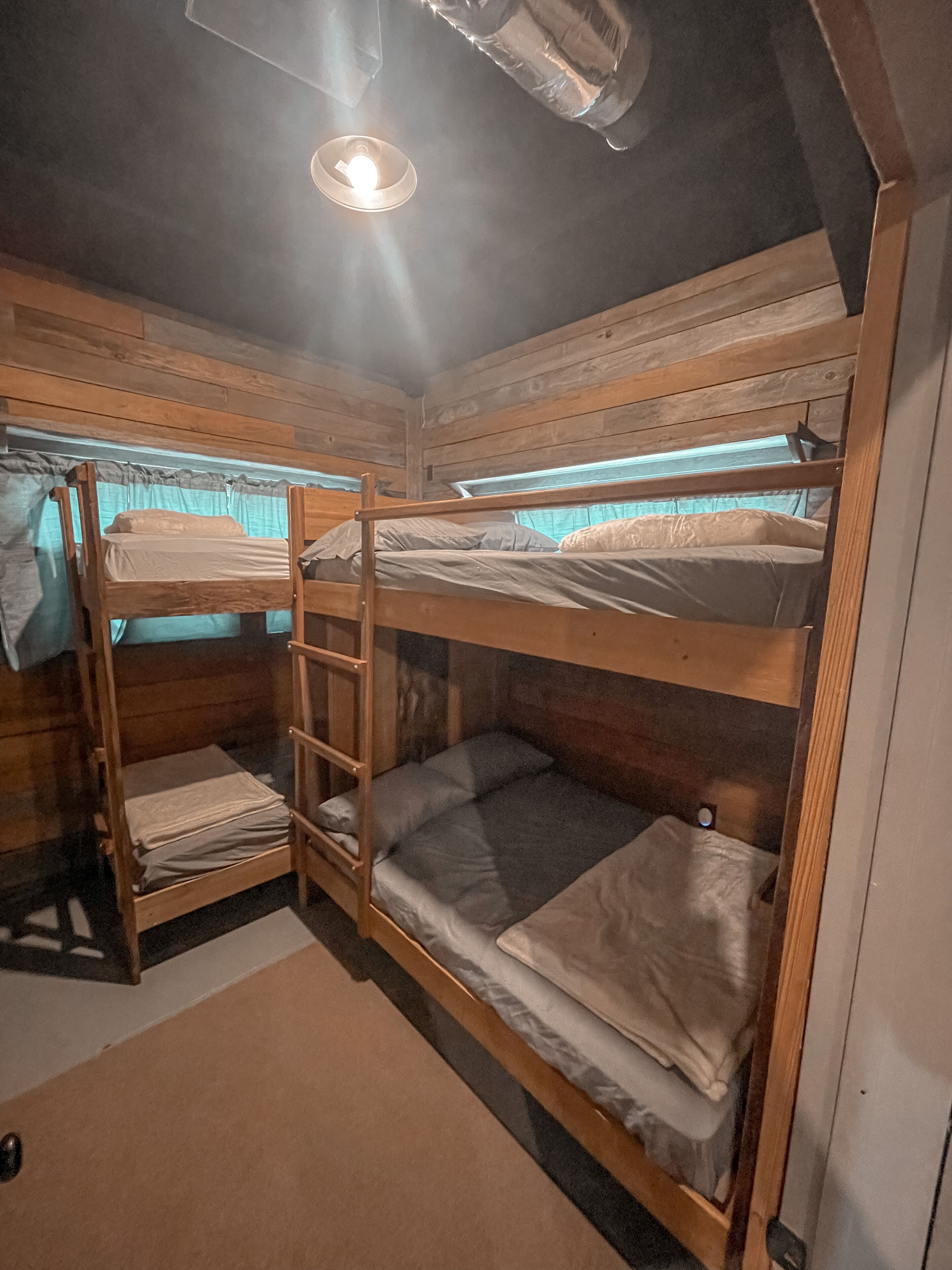 Habitación con literas, paredes de madera y una escalera.