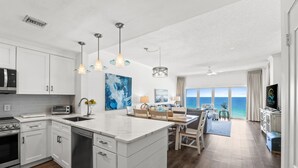 Une cuisine moderne avec des meubles blancs, un îlot central et des luminaires suspendus.