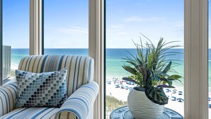 Una habitación con vista al mar, un sofá a rayas, un cojín estampado y una planta en una mesa redonda.