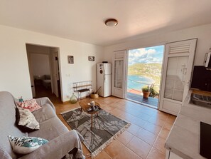 En stue med sofa, sofabord og havudsigt gennem en skydedør.